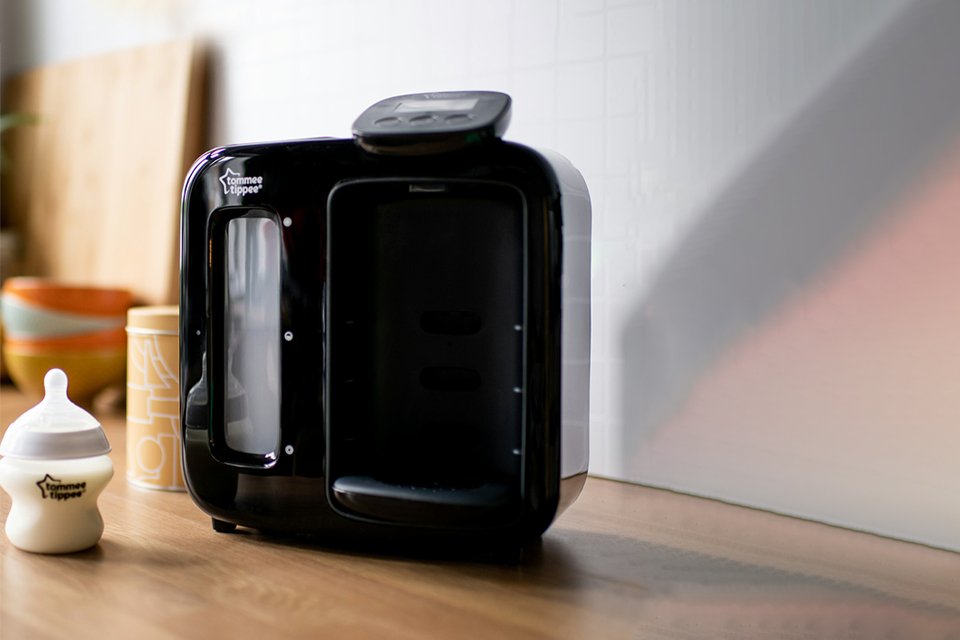 A Tommee Tippee perfect prep day & night machine in black colour placed with a bottle next to it.